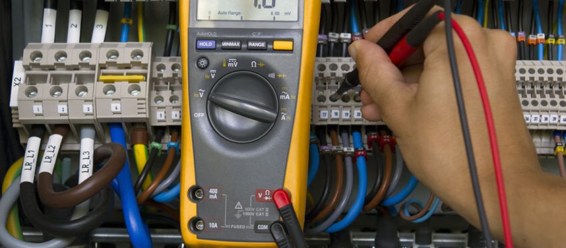 Electrician performing voltage measurements with electrical multimeter.